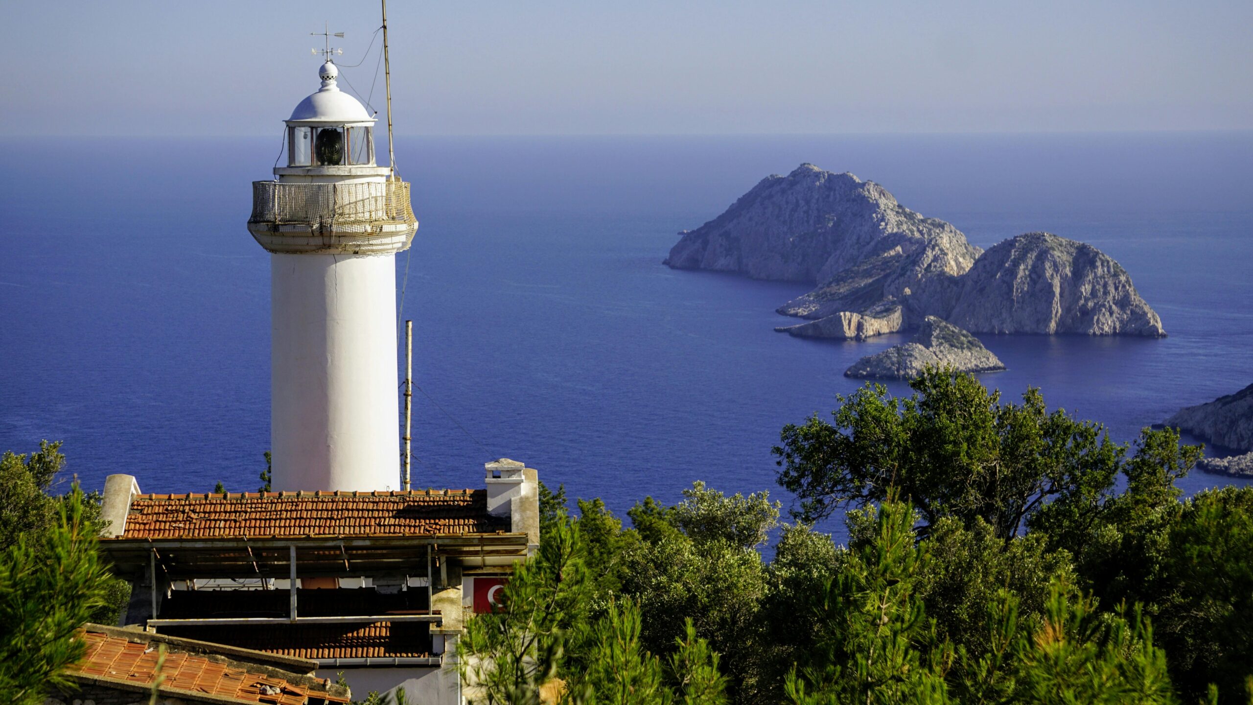 Lighthouse with ocean view and rocky islands in the Mediterranean coastline, tranquil travel destination.